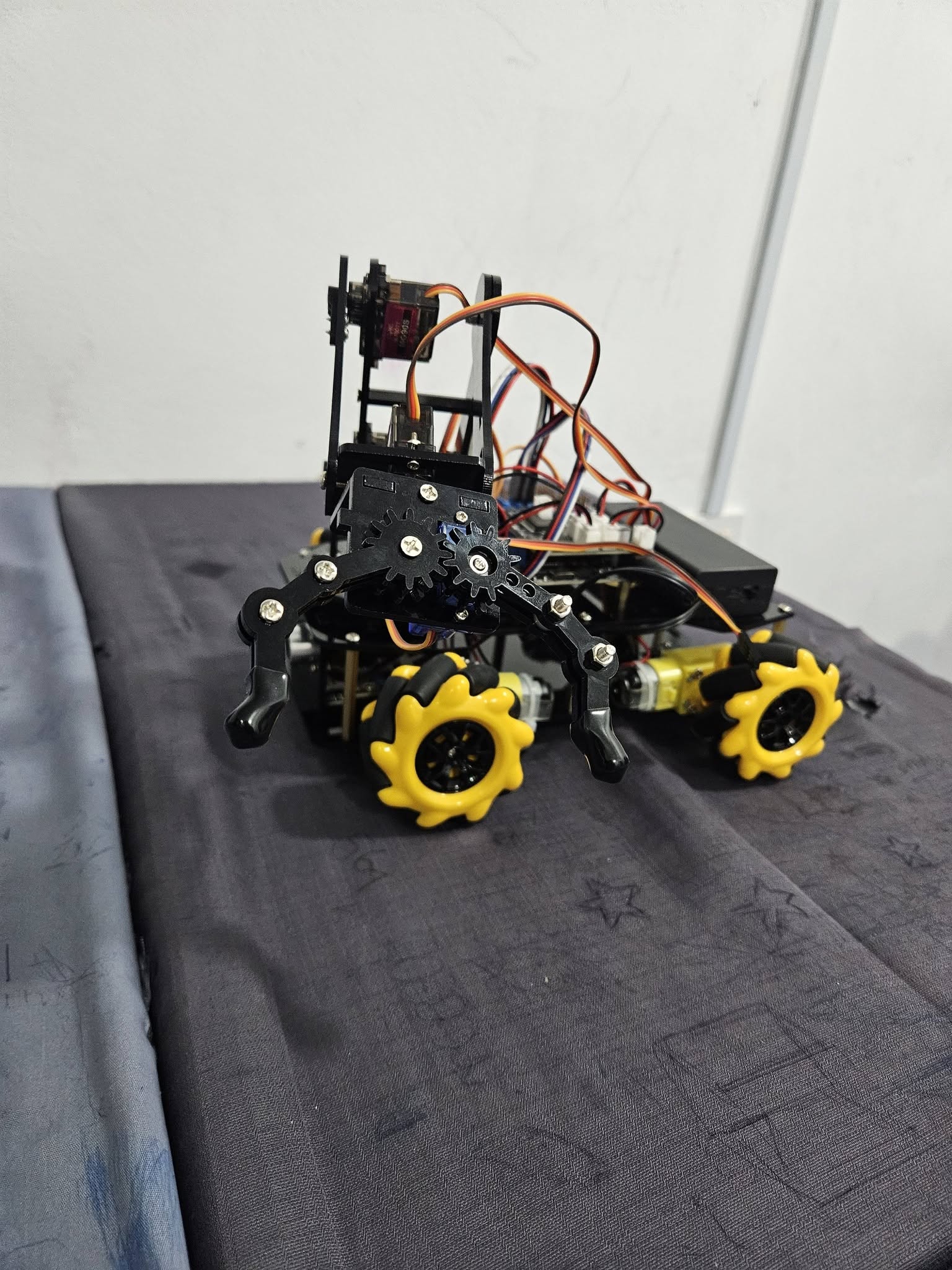 A completed robotics vehicle with a gripper mechanism and yellow wheels