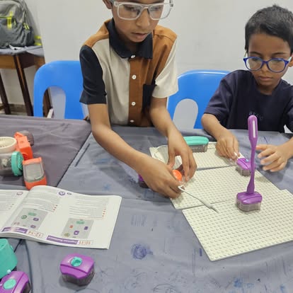 Children assembling a robotics build on a grid board